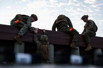 U.S. Marines with 5th Air Naval Gunfire Liaison Company, III Marine Expeditionary Force Information Group, and 9th Engineer Support Battalion, 3rd Marine Logistics Group, climb an obstacle course wall during a Marine Corps Martial Arts Program black belt culminating event at Camp Hansen, Okinawa, Japan, Feb. 26, 2026.
