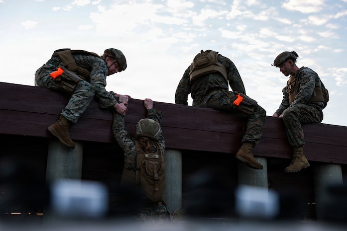 U.S. Marines with 5th Air Naval Gunfire Liaison Company, III Marine Expeditionary Force Information Group, and 9th Engineer Support Battalion, 3rd Marine Logistics Group, climb an obstacle course wall during a Marine Corps Martial Arts Program black belt culminating event at Camp Hansen, Okinawa, Japan, Feb. 26, 2026.