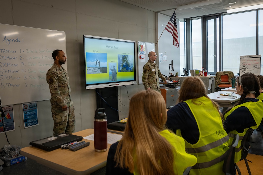 Two U.S. Air Force members talk to a classroom of middle school students.