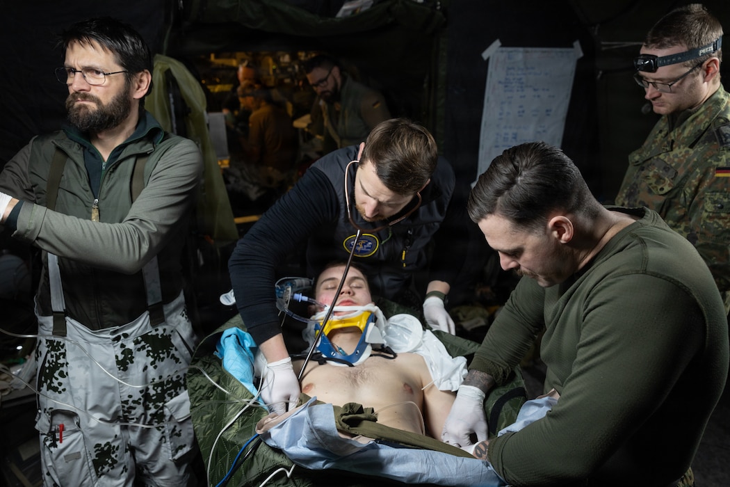 260204-M-RU058-1144 U.S. Navy Hospital Corpsman 1st Class Zachary Matthews, bottom right, with Combat Logistics Battalion 6, Combat Logistics Regiment 2, 2nd Marine Logistics Group, inserts an intravenous needle on a simulated casualty during Medical Reindeer in Setermoen, Norway, Feb. 4, 2026. Medical Reindeer is a multinational medical exercise where military medical teams from different NATO countries practice saving lives together in a realistic field environment. A key component of NATO's enhanced vigilance activity Arctic Sentry, exercise Cold Response 26 is a Norwegian-led winter military exercise designed to enhance collective defense capabilities and ensure U.S. readiness to rapidly deploy and seamlessly operate alongside NATO Allies in challenging arctic conditions. Matthews is a native of Florida. (U.S. Marine Corps photo by Cpl. Apollo Wilson)