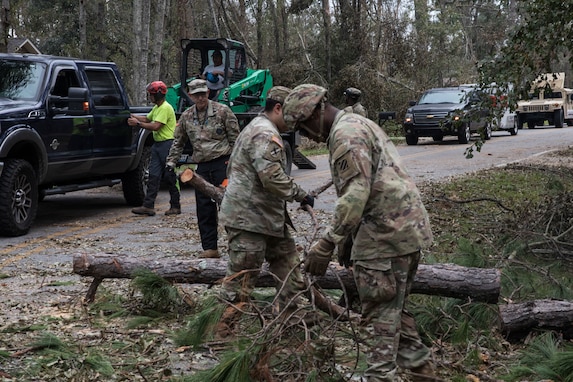 Georgia State Defense Force personnel and Soldiers with the Cumming-based 3rd Battalion, 121st Infantry Regiment, 48th Infantry Brigade Combat Team, Georgia Army National Guard, remove tree debris from the road in Swainsboro, Georgia, Oct. 1, 2024. The Georgia National Guard has mobilized to provide response and recovery support to areas in the state impacted by Hurricane Helene. At the direction of the Governor and through The Georgia Emergency Management and Homeland Security Agency (GEMA/HS), the Georgia National Guard will continue to partner local, state, and federal entities in this effort. (U.S. Army National Guard photo by Spc. Ayanna Tillman)