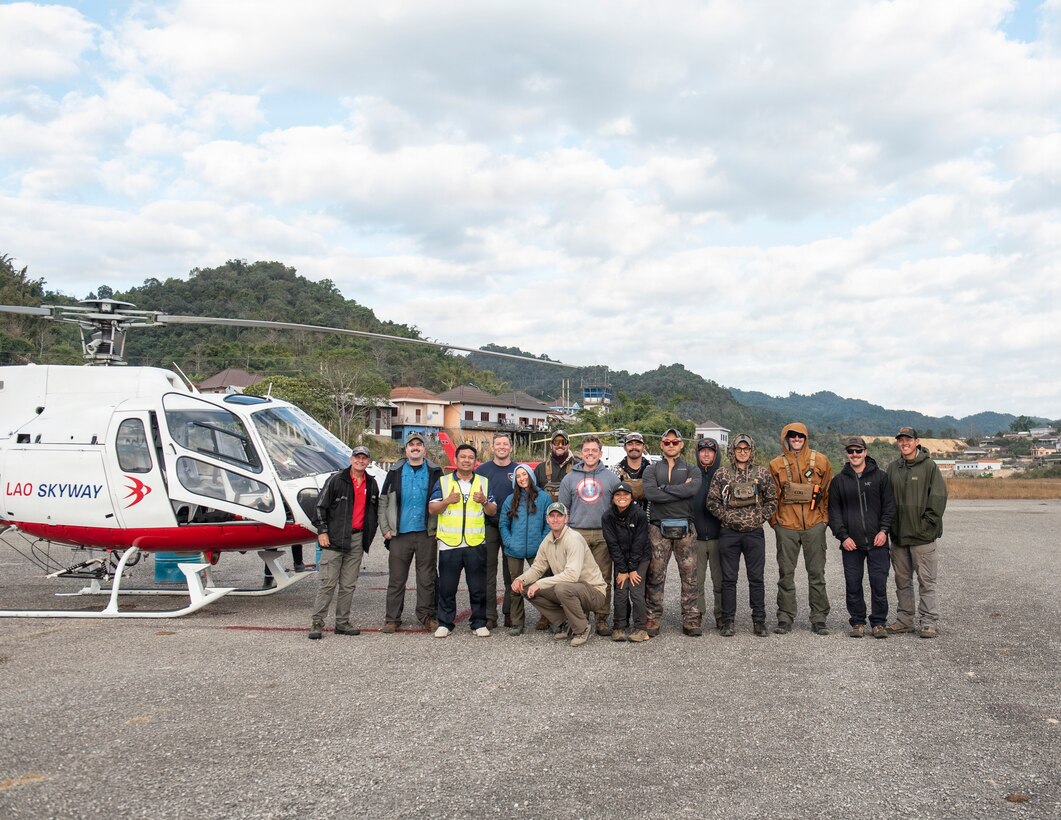 Defense POW/MIA Accounting Agency recovery team members and Lao Skyway members pose for a photo next to a Lao Skyway Helicopter, Jan. 24, 2026.