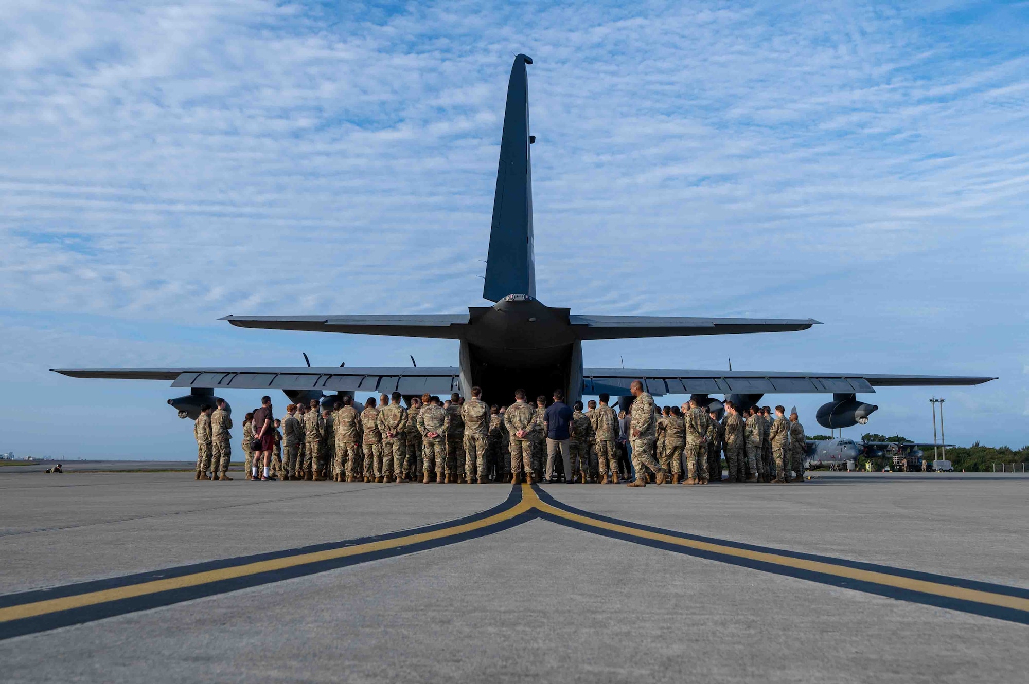 Service members gather around an aircraft for a memorial service.