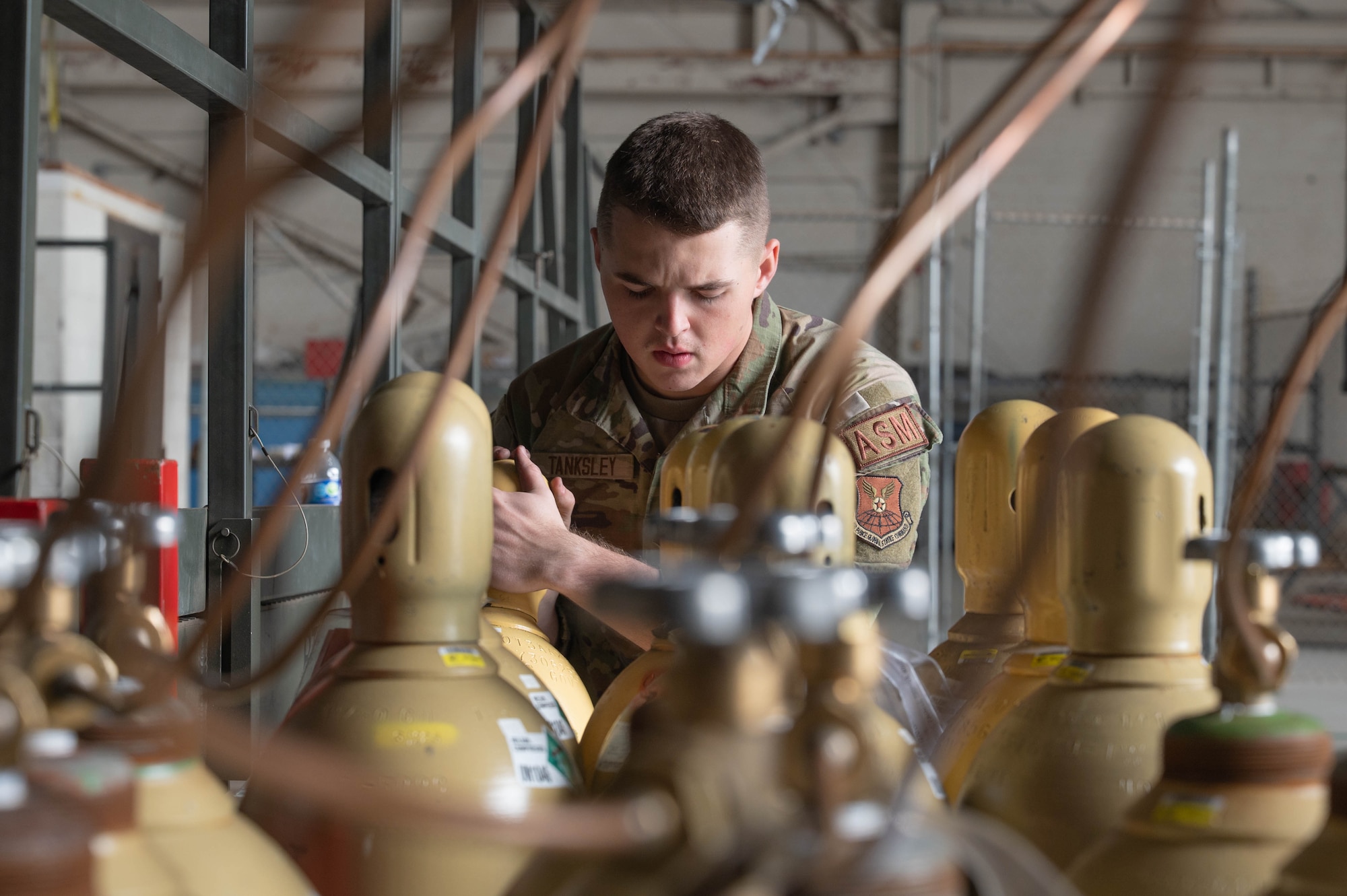 U.S. Air Force Airman 1st Class Andrew Tanksley, 7th Equipment Maintenance Squadron aircraft structural maintenance apprentice, moves a helium tank in support of a cold spray repair at Dyess Air Force Base, Texas, Feb. 20, 2026. The helium was used to accelerate aluminum powder particles bonding with a metal surface  during the structural repair of a B-1B Lancer component. (U.S. Air Force photo by Airman 1st Class William Neal)