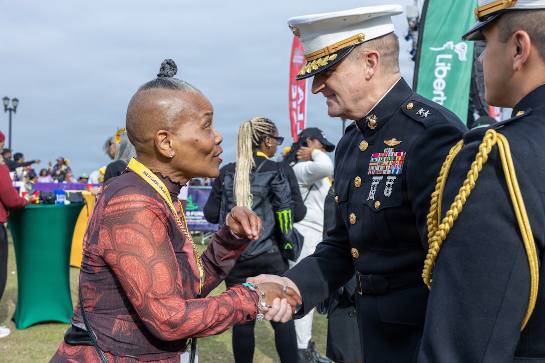 U.S. Marine Corps Maj. Gen. Douglas Clark, deputy commander of Marine Forces Reserve and Marine Forces South, shakes hands with a festival participant during Lundi Gras Festival at Woldenberg Park, Feb. 16, 2026. Maj. Gen. Clark celebrated Lundi Gras with the Zulu Social Aid and Pleasure Club, emphasizing the tradition and long-standing partnership built over the years. (U.S. Marine Corps photo by Sgt. Emely Gonzalez)