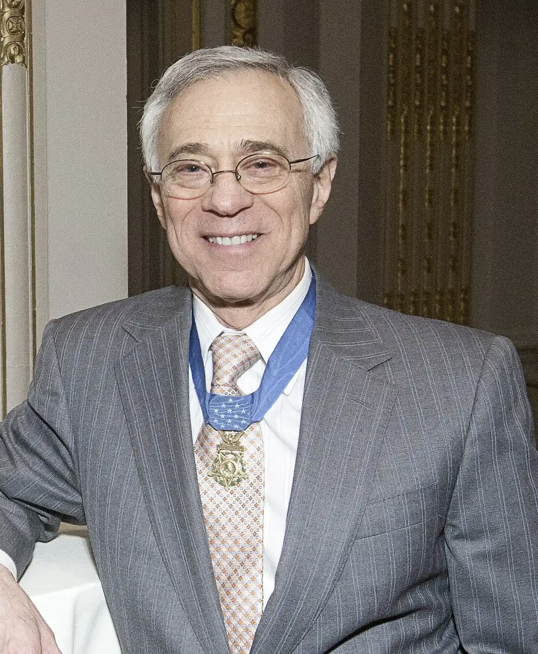 A man wearing a business suit smiles for a photo.