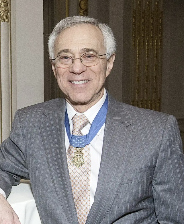 A man wearing a business suit smiles for a photo.