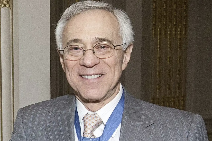 A man wearing a business suit smiles for a photo.