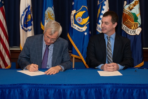 Image of two men signing documents.