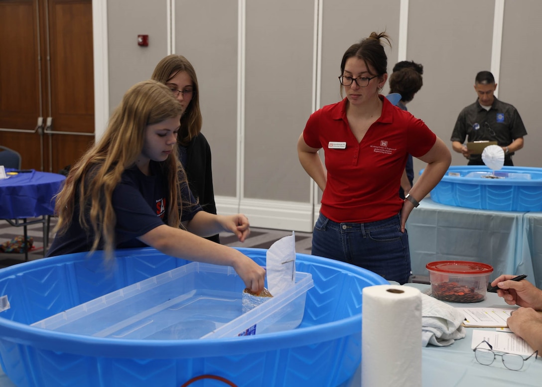 Students from St. Mary’s Middle School carefully place coins into their model boats while testing design stability during the first engineering challenge at the 24th Annual Engineering Career Day Feb. 27, 2026, in Jacksonville, Florida. U.S. Army Corps of Engineers volunteers helped guide participants as they evaluated buoyancy, weight distribution and structural performance. (U.S. Army Corps of Engineers photo by Aaron Church)