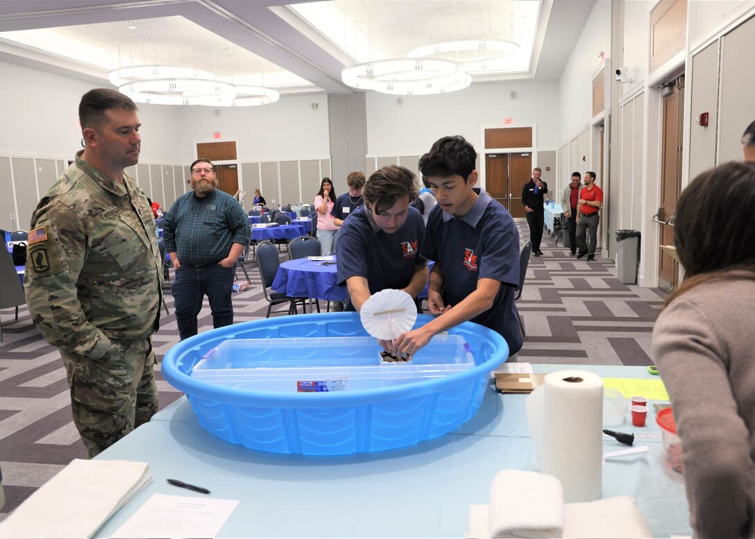 Lt. Col. Matthew Westcott, deputy commander of the U.S. Army Corps of Engineers Jacksonville District observes students from as they begin testing their boat designs during the first “Surprise Problem” challenge at the 24th Annual Engineering Career Day Feb. 27, 2026, in Jacksonville, Florida. Teams constructed small boats using limited materials and added coins to evaluate buoyancy and structural stability. (U.S. Army Corps of Engineers photo by Aaron Church)