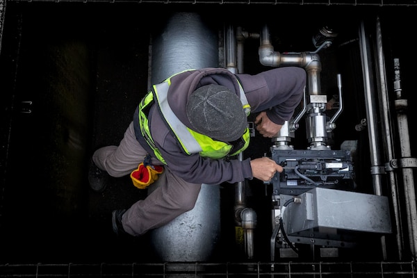 A man adjusts a machine in a concrete structure.