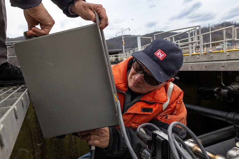 A man inspects a metal box.