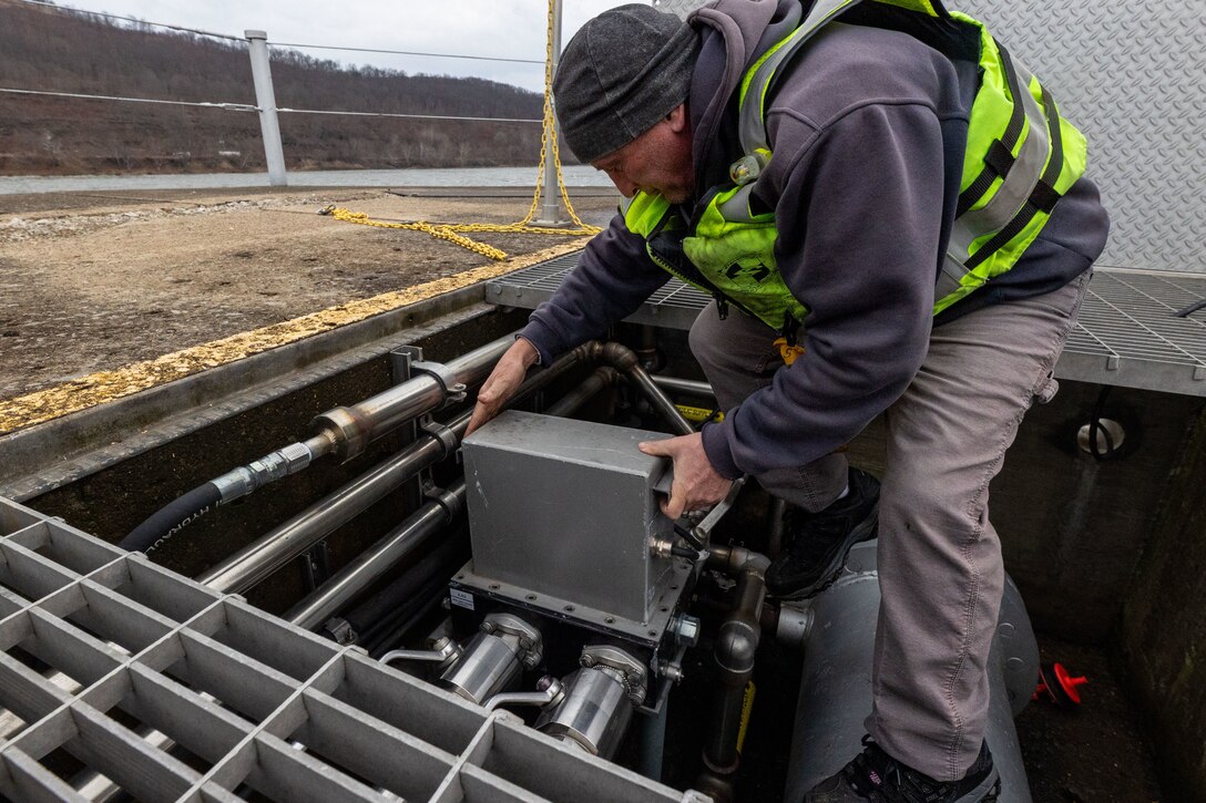 A man installs a metal box in a concrete structure.