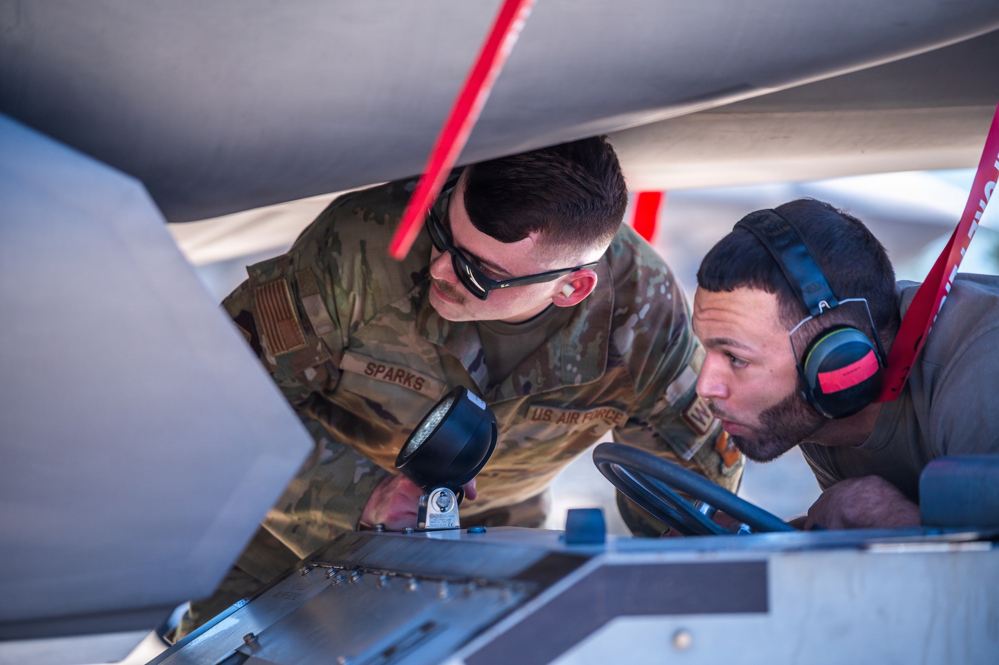 U.S. Air Force Staff Sgt. Wyatt Sparks (center), 56th Maintenance Group squadron lead crew chief, and Senior Airman Marc Colon (right), 63rd Aircraft Maintenance Unit weapons load crew member, participate in an annual weapons load competition, Feb. 27, 2026, at Luke Air Force Base, Arizona.