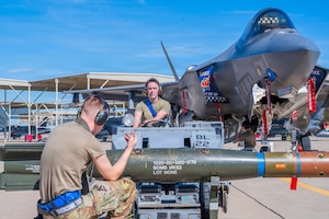 U.S. Air Force Senior Airman Keyden Petersen (center), 62nd Aircraft Maintenance Unit weapons load crew member, and Staff Sgt. Derek Rushing (left), 62nd Aircraft Maintenance Unit weapons load crew chief, participate in an annual weapons load competition, Feb. 27, 2026, at Luke Air Force Base, Arizona.