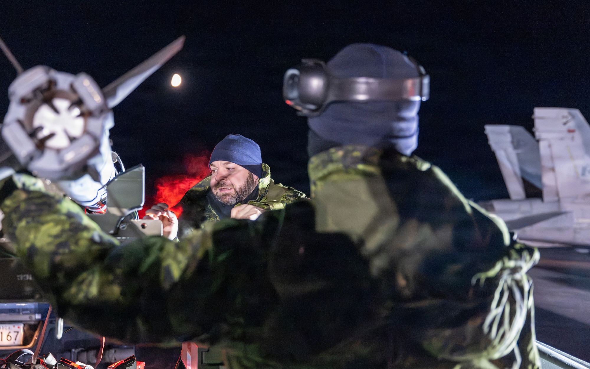Two Canadian service members stand next to an aircraft wing tip preparing it for takeoff.