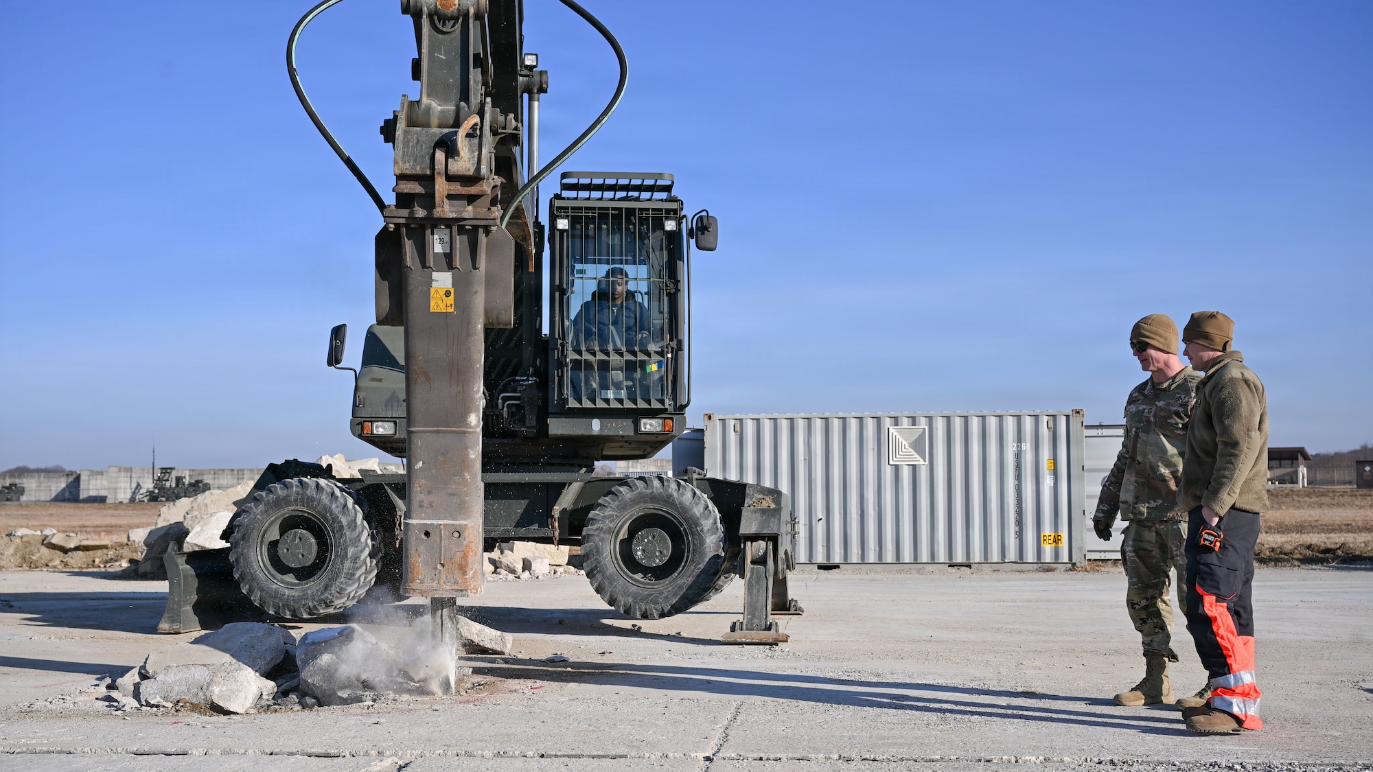 U.S. Air Force Senior Airman Delroy Williams, 51st Civil Engineer Squadron pavement and construction heavy equipment operator, breaks up ground with an excavator during Rapid Osan Airfield Recovery training at Osan Air Base, Republic of Korea, Feb. 26, 2026. The training evaluated the placement of flowable fill concrete over crushed stone using a volumetric mixer to rapidly restore limited runway capability under the Rapid Osan Airfield Recovery concept. (U.S. Air Force photo by Senior Airman Rome Bowermaster)