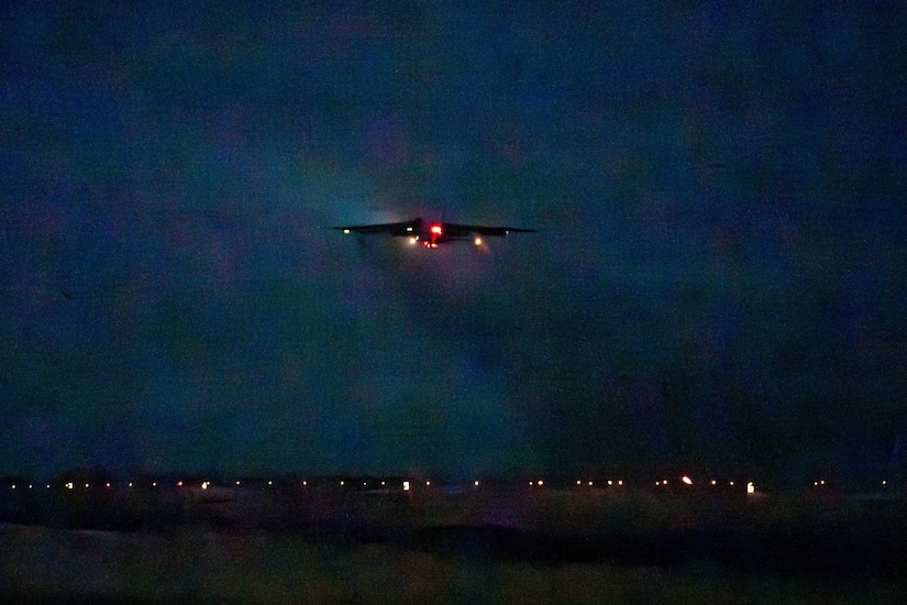 A silhouette of a combat aircraft can be seen in the night sky.