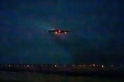 A silhouette of a combat aircraft can be seen in the night sky.