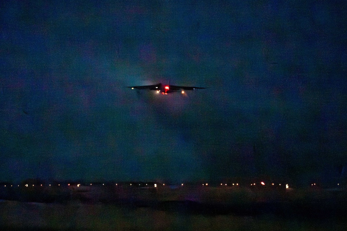A silhouette of a combat aircraft can be seen in the night sky.