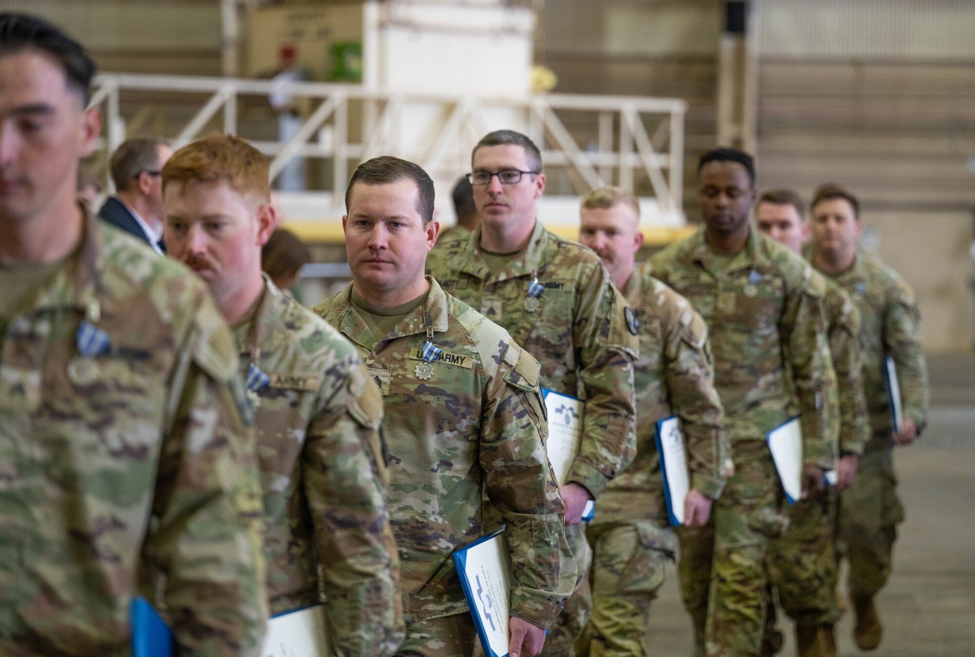 Members of the 5-5 Air Defense Artillery Battalion, assigned to Fort Sill, walk back to their seats after being awarded the Air and Space Achievement Medal at Altus Air Force Base, Oklahoma, March 4, 2026. From weight distribution and tie-down configurations to communication protocols, every step is critical in the process of executing proper loading procedures for Army combat vehicles onto the C-17 Globemaster III aircraft. (U.S. Air Force photo by Airman 1st Class Emma Wright)