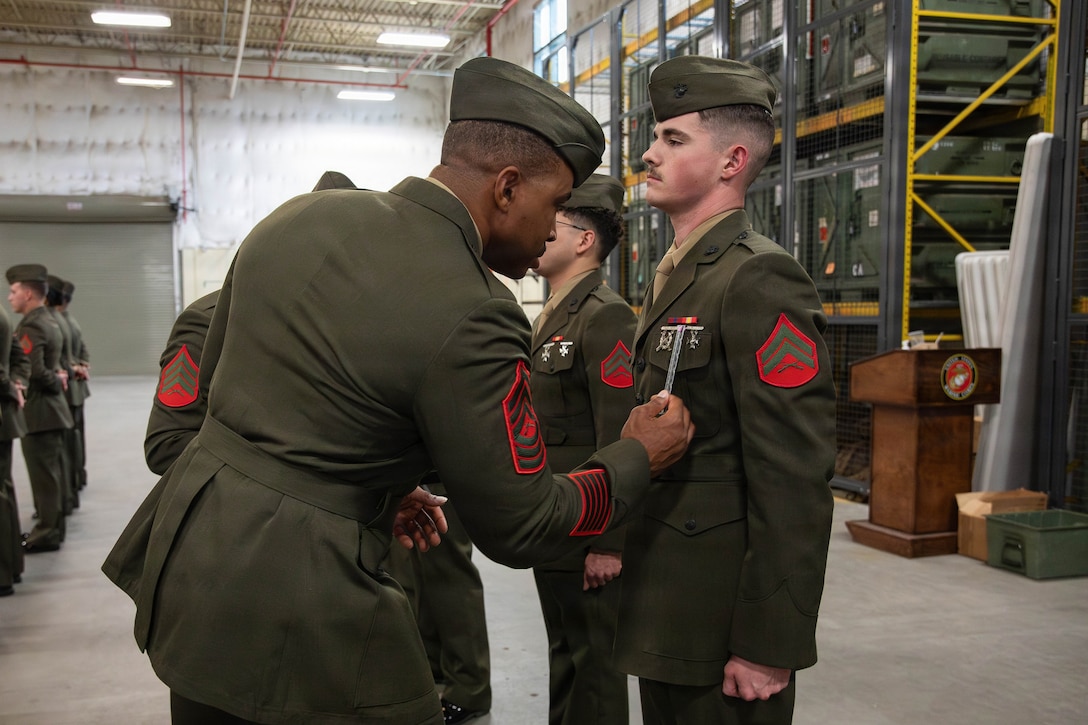 U.S. Marine Corps Master Sgt. Kevin Ross, a systems planning engineer with Headquarters Battalion, Marine Forces Reserve, checks for the placement of shooting badges on Cpl. Matthew Hysler, military police officer, Marine Forces Reserve, during a service alpha uniform inspection, Marine Corps Support Facility New Orleans, Feb. 27, 2026. The inspection was conducted to evaluate the Marines’ appearance and adherence to standards while promoting discipline and attention to detail. (U.S. Marine Corps photo by Lance Cpl. Van Hoang)