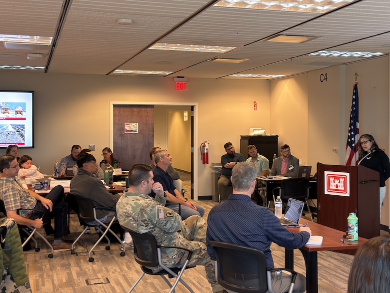 Group of people listening to a presentation in a conference room.