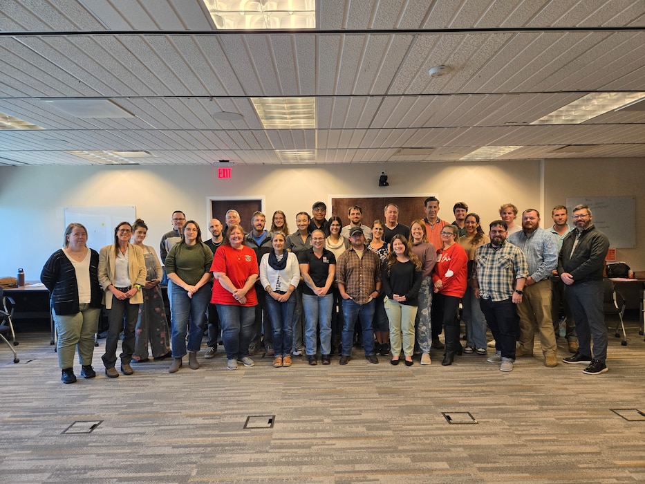 Photo of a group of people standing together in a conference room.