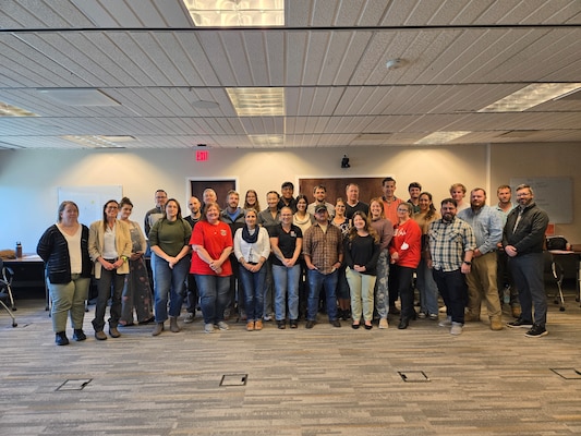 Photo of a group of people standing together in a conference room.