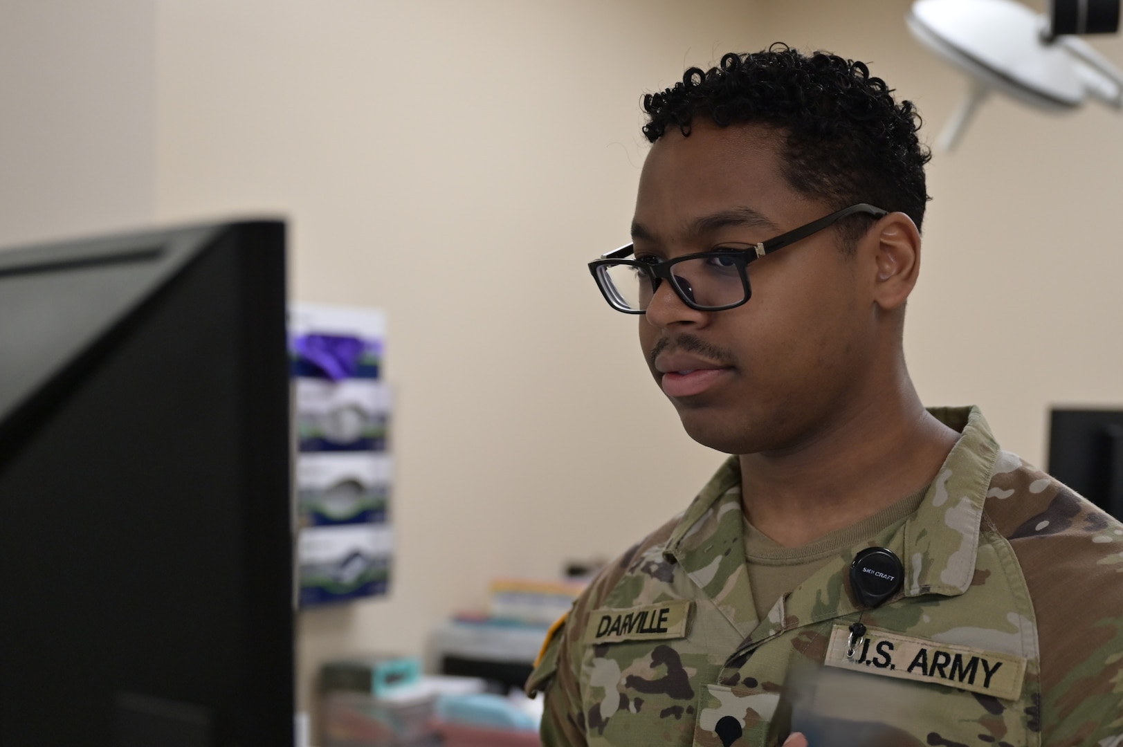 Spc. Noah Darville, an orthopedic technician at Carl R. Darnall Army Medical Center, reviews patient information prior to confirming the details with the patient before assisting Alex Morales, an orthopedic physician assistant, during a patient procedure in the Orthopedic Clinic.