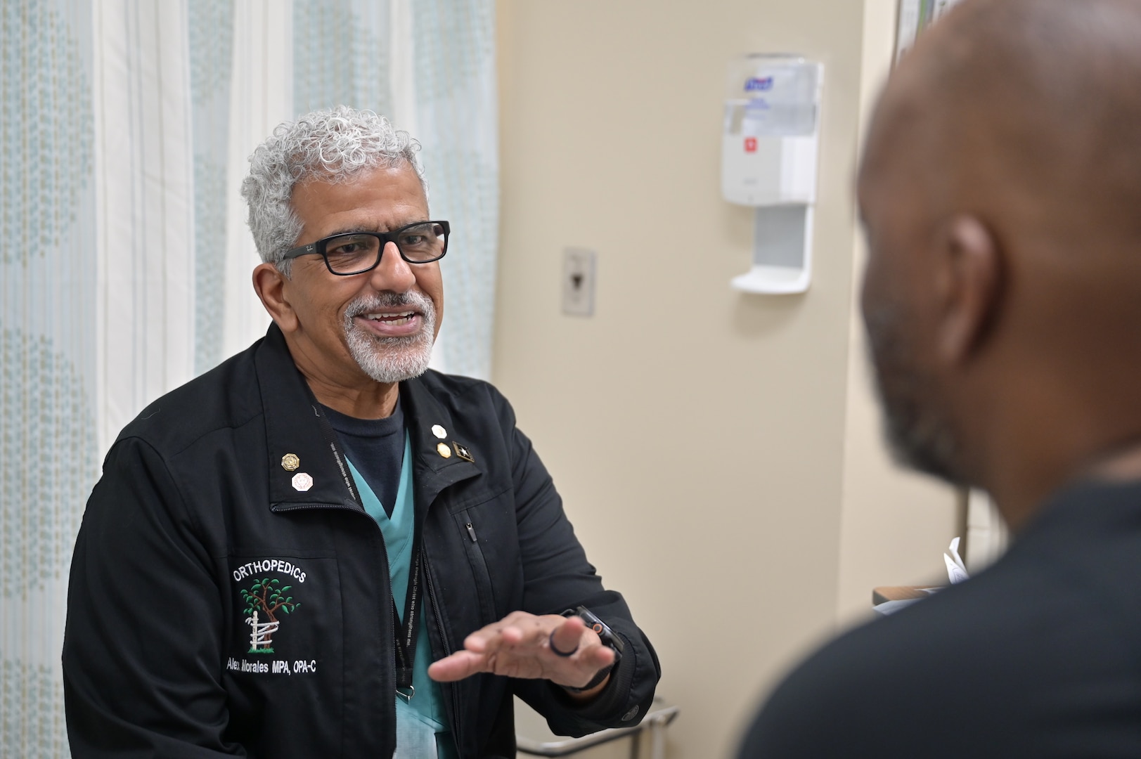 Alex Morales, an orthopedic physician assistant at Carl R. Darnall Army Medical Center, speaks with a patient during an appointment in the Orthopedic Clinic. Providers emphasize communication and teamwork to support patient care for Soldiers, family members, and retirees.