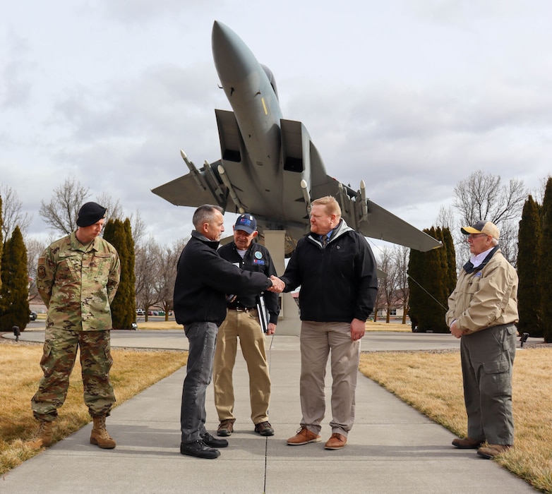 People shake hands in front of F-16 static display