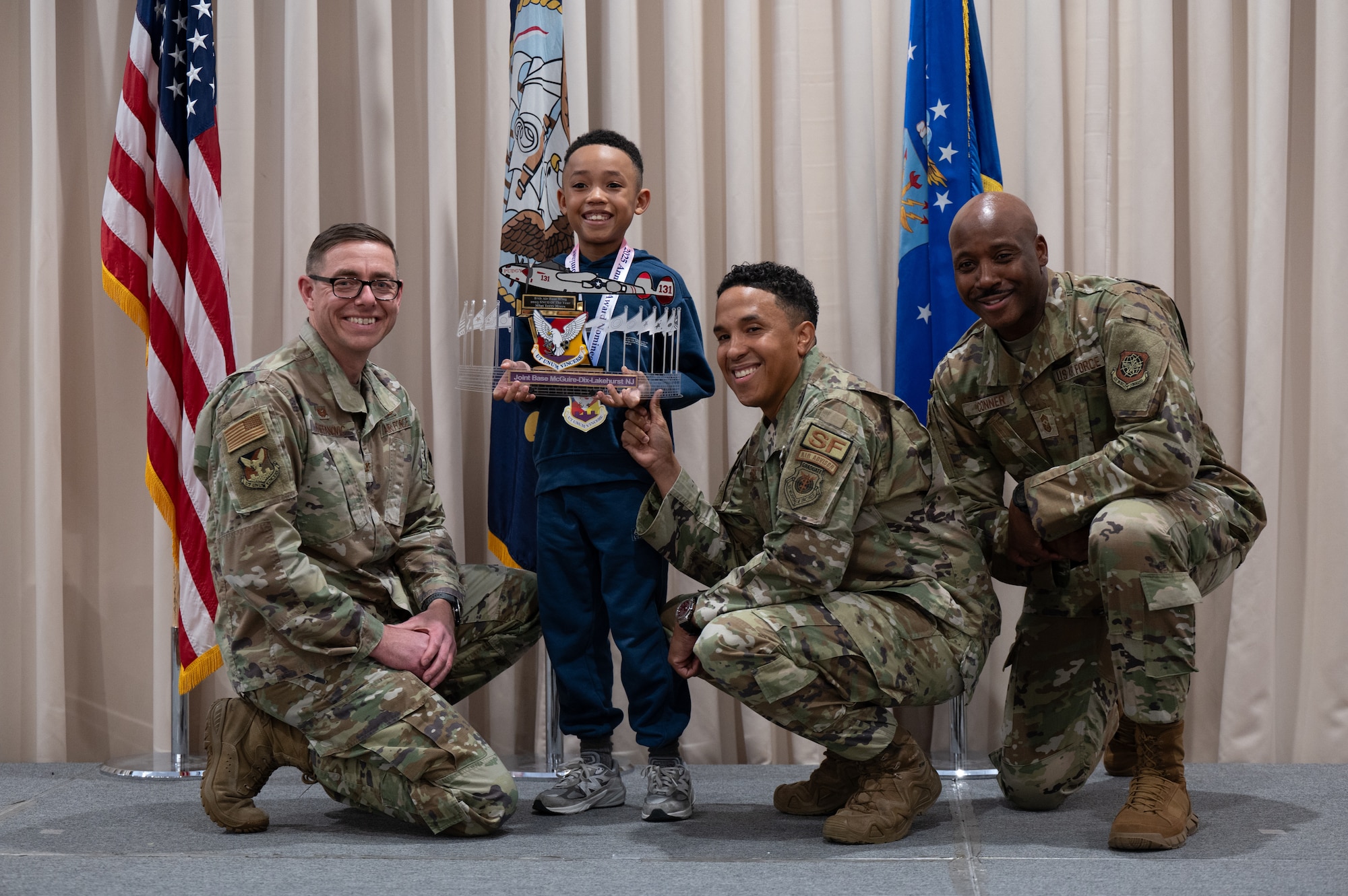 U.S. Air Force Master Sgt. Terry Myers, center right, 21st Air Force and U.S. Air Force Expeditionary Center combat support doctrine manager, and his son, accepts the 87th Air Base Wing Senior Noncommissioned Officer of the year award from Col. Michael Stefanovic, left, Joint Base McGuire-Dix-Lakehurst and 87th ABW commander, and Chief Master Sgt. Nicholas Conner, 87th ABW command chief, at JB MDL, N.J., Feb. 26, 2026.