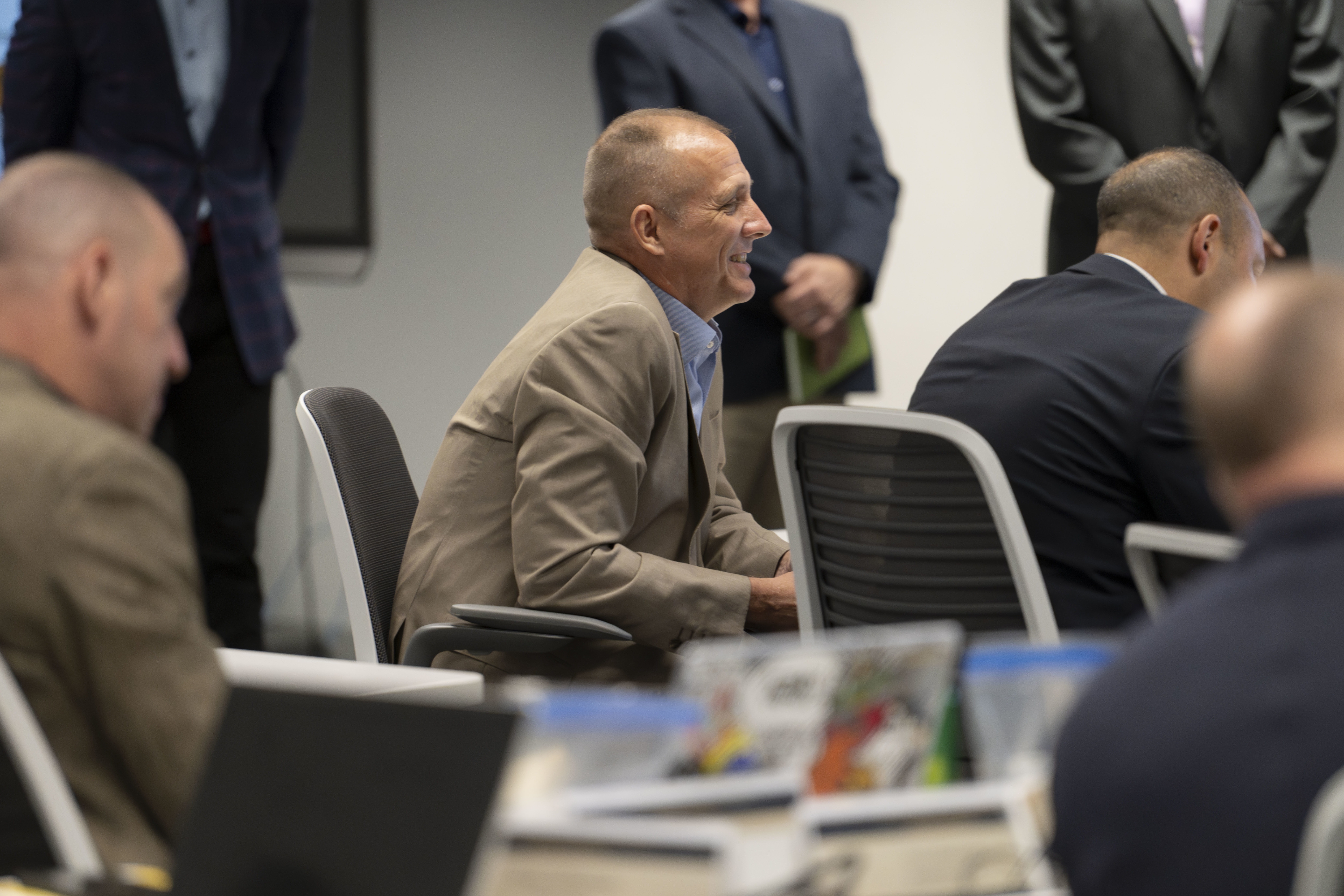 Student seated in the audience listens attentively to an instructor speaking at the front of the room.