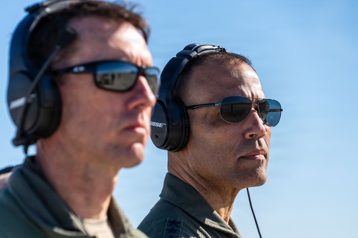 A close up of General Adrian Spain's and Brigadier General David Epperson's face as they look off camera with ear protection on.
