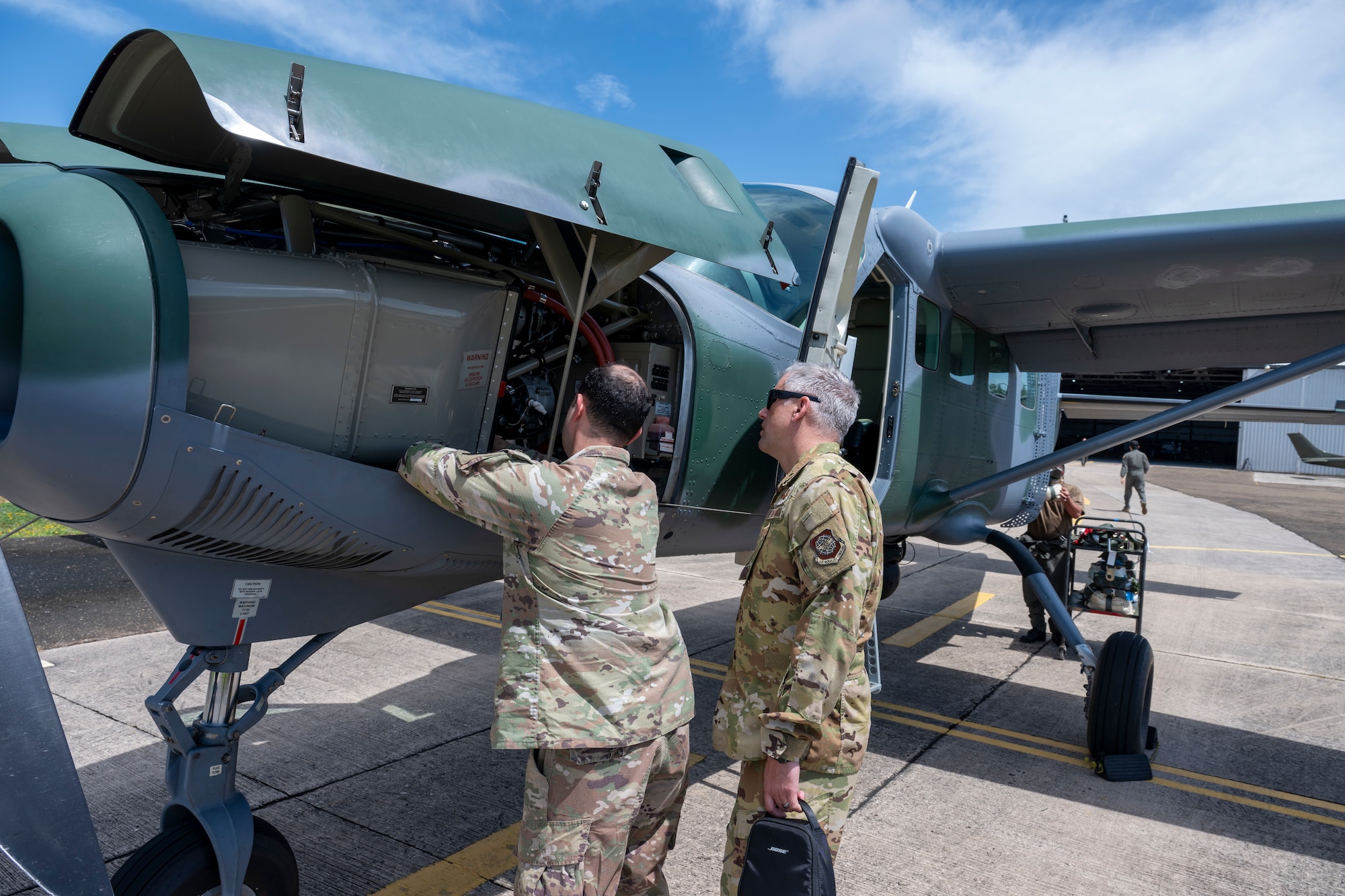 Two men look at airplane engine.