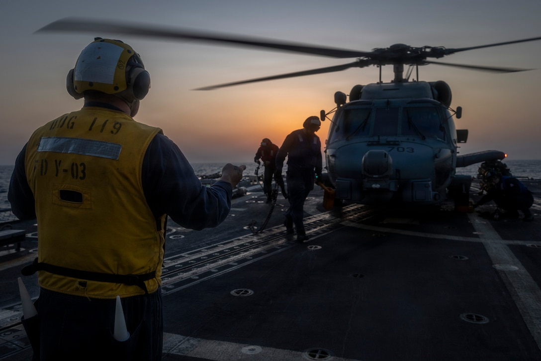 A U.S. Sailor assigned to Arleigh Burke-class guided-missile destroyer USS Delbert D. Black (DDG 119) directs an MH-60R Sea Hawk helicopter, attached to Helicopter Maritime Strike Squadron (HSM) 46, during a flight quarter evolution in the U.S. Central Command area of responsibility in support of Operation Epic Fury, Mar. 7, 2026. (U.S. Navy photo)