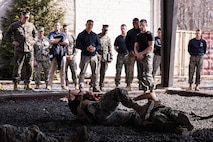 The Honorable Hung Cao, Under Secretary of the Navy, center, and U.S. Marines with The Basic School, observe a Marine Corps Martial Arts Program demonstration at Marine Corps Base Quantico, Virginia, Feb. 27, 2026. During a visit to TBS and Officer Candidates School, Cao met with senior leaders and Marines to observe training and gain a deeper understanding of the methods the Marine Corps uses to train, screen, and evaluate its candidates and newly commissioned officers.