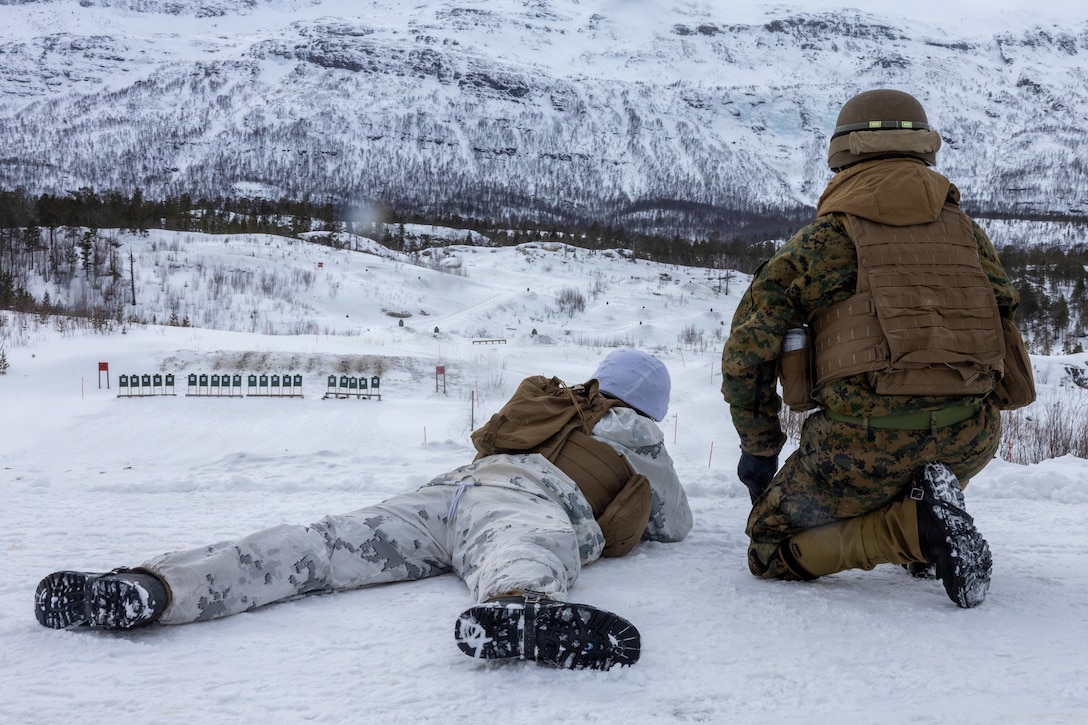 U.S. Marine Corps Lance Cpl. Jimmy Torresviana, left, an engineer equipment mechanic with Combat Logistics Battalion 6, Combat Logistics Regiment 2, 2nd Marine Logistics Group, fires his M16A4 service rifle while Cpl. Jesse Galindomunoz, a food service specialist with CLB-6, acts as a position safety officer in Setermoen, Norway, March 4, 2026. The Marines participated in a modified marksmanship program that required firing from unknown distances to enhance their combat readiness for exercise Cold Response 26. A key component of NATO's enhanced vigilance activity Arctic Sentry, exercise Cold Response 26 is a Norwegian-led winter military exercise designed to enhance collective defense capabilities and ensure U.S. readiness to rapidly deploy and seamlessly operate alongside NATO Allies in challenging arctic conditions. Torresviana is a native of Florida, and Galindomunoz is a native of California. (U.S. Marine Corps photo by Cpl. Apollo Wilson)