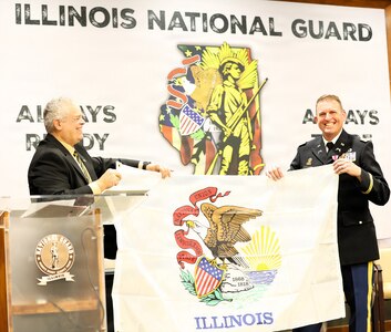Lt. Col. Justin Wilkerson of the Illinois Army National Guard and Illinois State Rep. Dan Swanson share a laugh while posing for a photo with the Illinois State Flag during Wilkerson’s retirement ceremony.