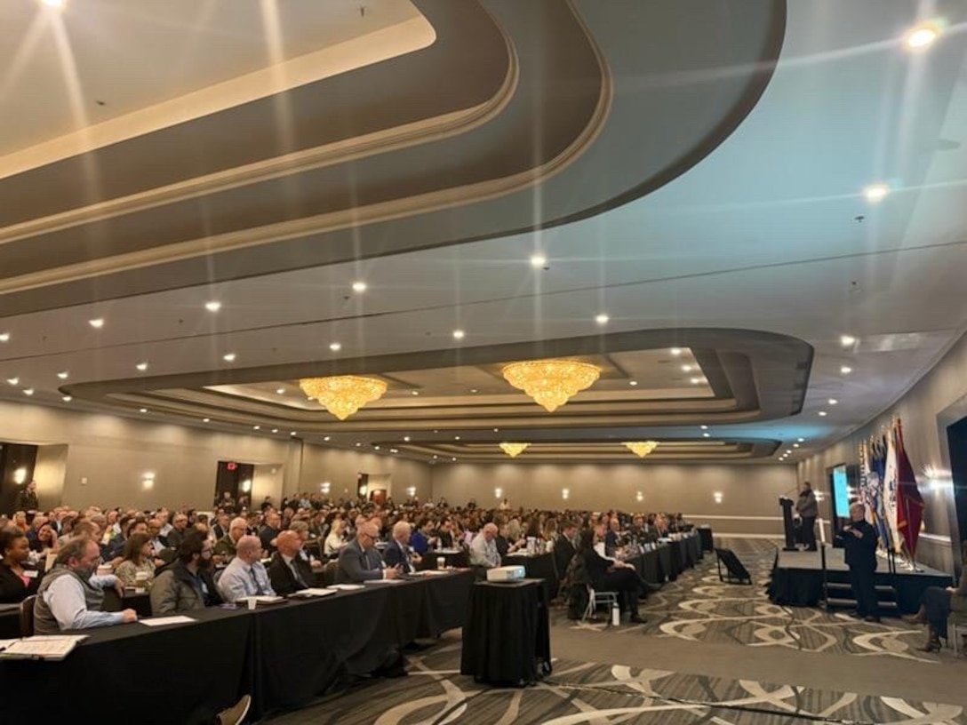 hundreds of people sit at conference tables