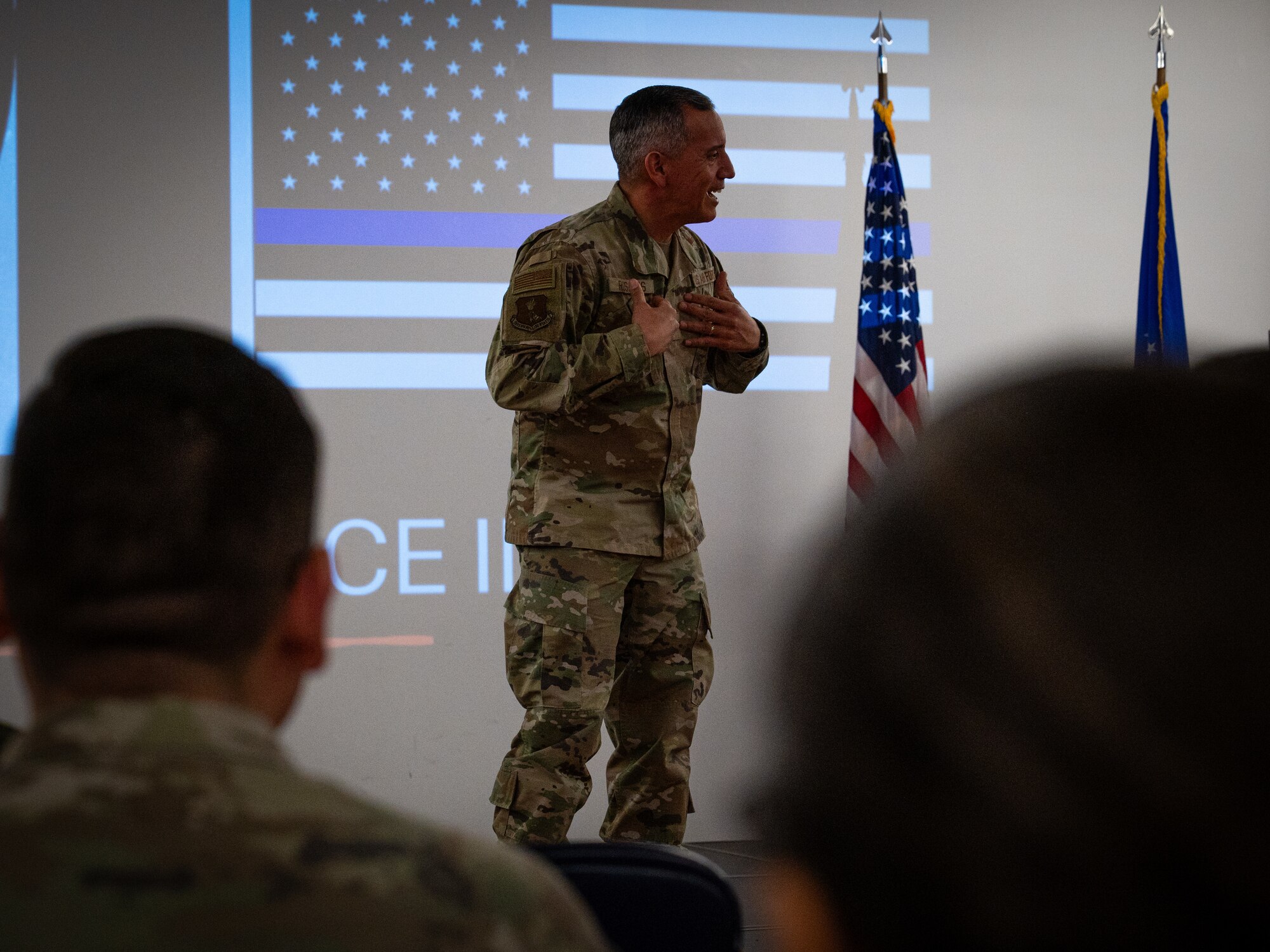 A photo of a man standing a stage speaking to a crowd.