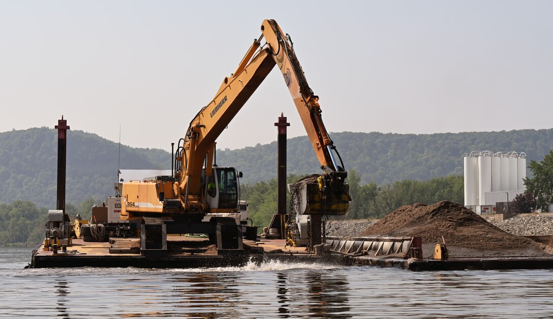 Construction equipment on a barge removes dredged material from the water.