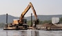 Construction equipment on a barge removes dredged material from the water.