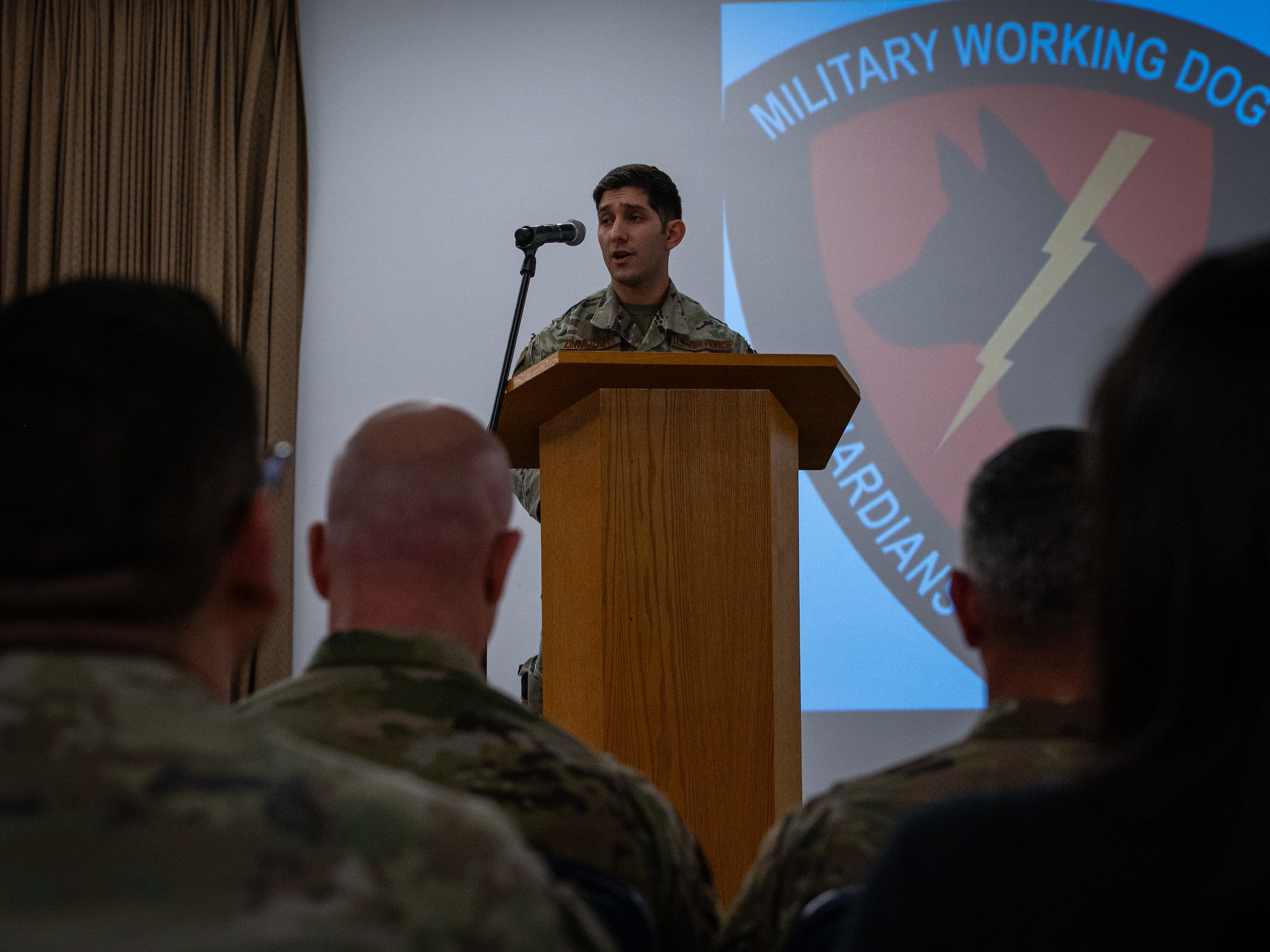 A photo of a man standing on a stand, speaking.
