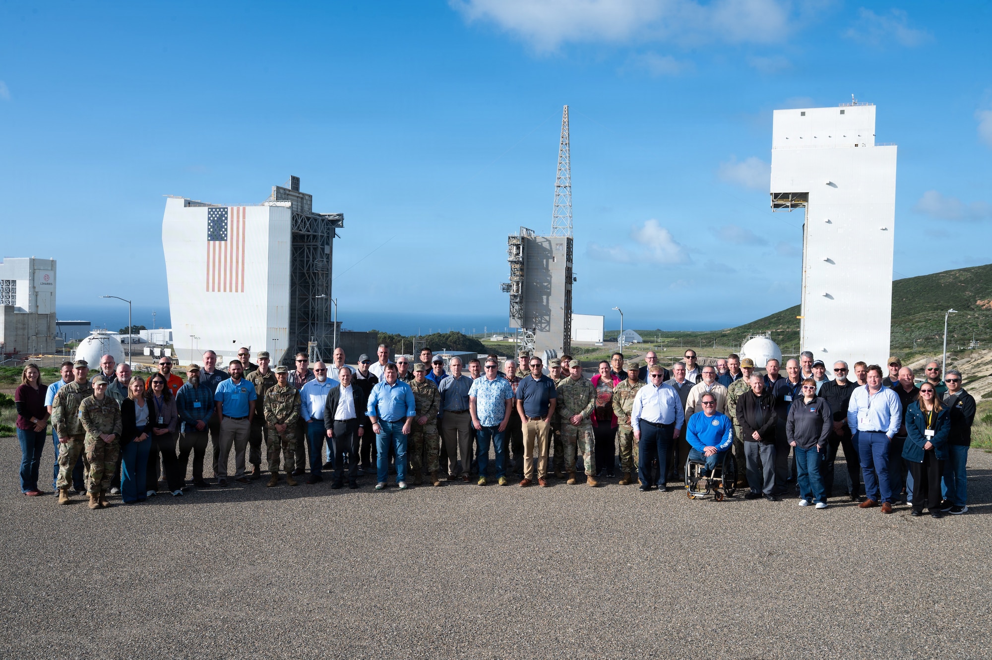 a group of people gather for a photo in front of a space launch complex