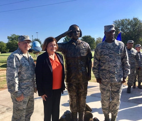 four individuals pose near statue