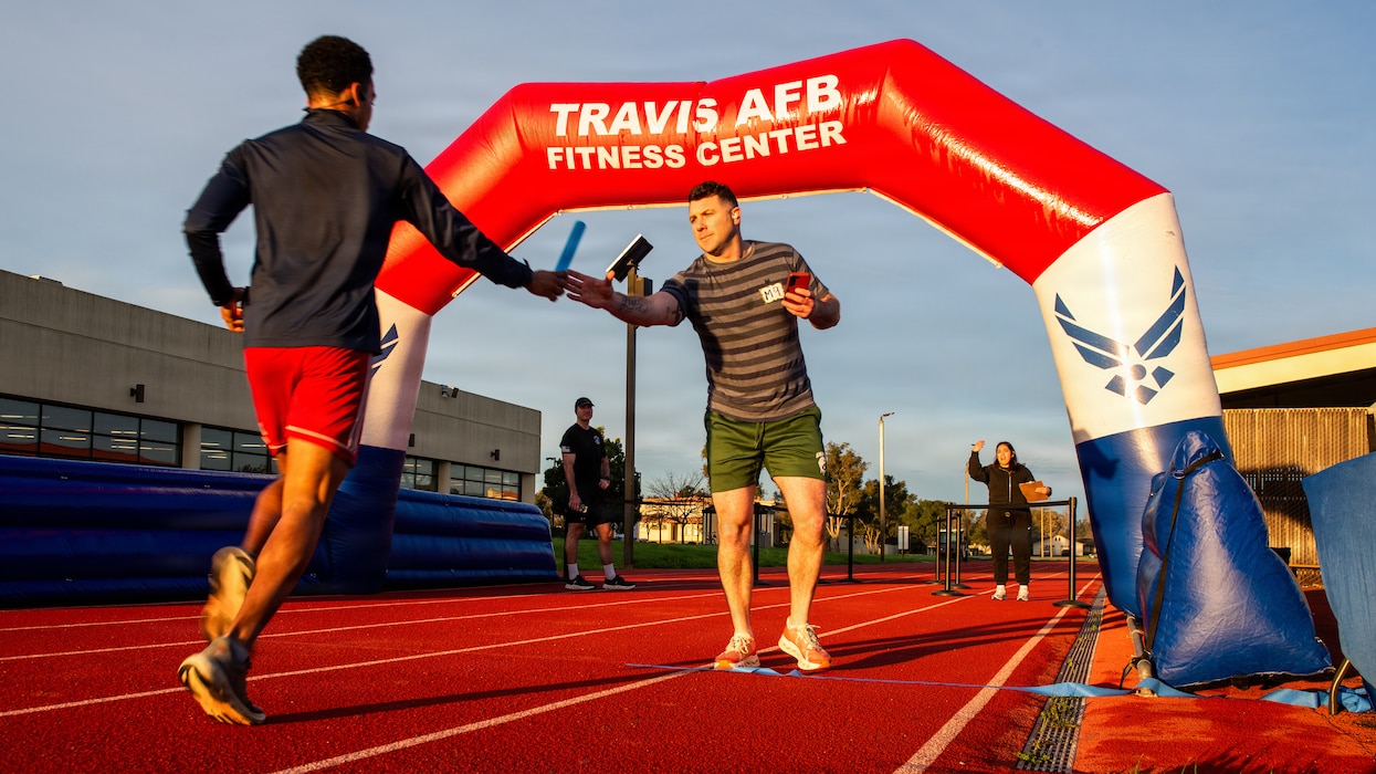 Airmen at the starting line exchanging a baton