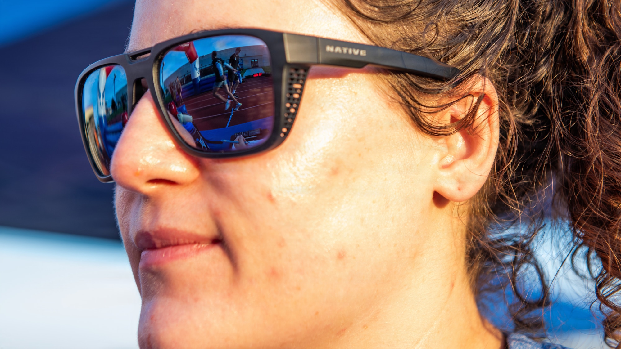 Close up of civilian's glasses showing Airmen exchanging a baton